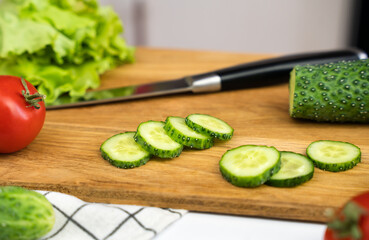 Preparing a salad from cucumbers, tomatoes and herbs. Dietary salad. Close-up. Selective focus.