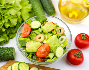 Dietary vegetable salad of cucumbers, tomatoes, olives and herbs. Healthy food concept. Close-up. Top view. Selective focus.