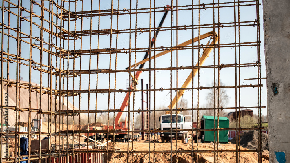 Poster construction site with concrete framework and machinery in progress during the day