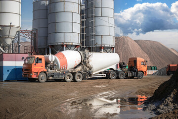Construction trucks loading concrete at a manufacturing facility in the afternoon sunlight