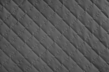 Obraz premium Checkered, diamond stitching pattern, black quilted fabric background. Blanket or puffer jacket, stitch rhombus texture close up, macro. Wallpaper, backdrop.