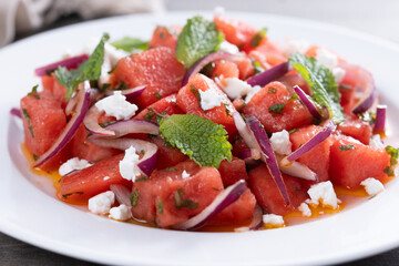 Fresh Watermelon Feta Salad with Mint and Red Onion on wooden table. Close up
