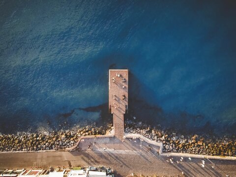 Aerial view of a pier extending into the blue sea. - Powered by Adobe