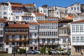 Scenic view from Praza a Enrique Ivntiga Eira Vella, Betanzos, Galicia, with riverside white homes and boats reflecting on the peaceful Mandeo River.