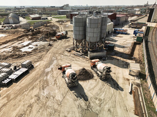 Construction site with concrete mixers and storage silos in an industrial area