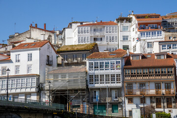 Scenic view from Praza a Enrique Ivntiga Eira Vella, Betanzos, Galicia, with riverside white homes and boats reflecting on the peaceful Mandeo River.