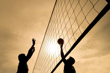 Silhouette of Volleyball Players Jumping During Outdoor Match at Sunset

