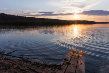 Beautiful sunset over a tranquil lake, featuring a wooden pier