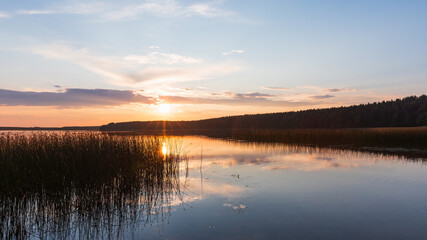 Panoramic photo featuring tranquil sunset view over a calm lake