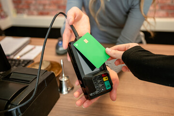 hand of woman paying by credit card at store in credit card reader