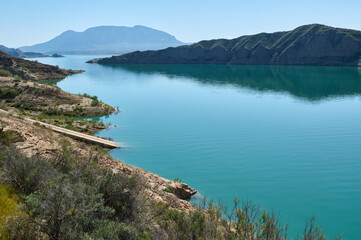 Scenic View of a Serene Lake Surrounded by Hills and Clear Skies
