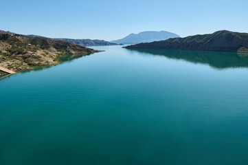 Panoramic View of a Tranquil Blue Reservoir Surrounded by Hills Under a Clear Sky