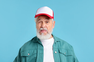 Elderly man in stylish outfit on light blue background
