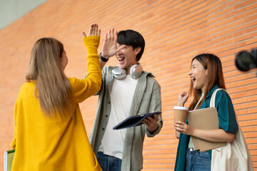 Students at university with fun for learning,Walking,laughing and bonding and talking.asian group of gen z friends student giving high five outdoor with books ready for education at college campus.