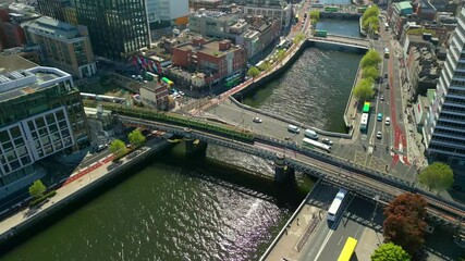 A train passing over the River Liffey, next to Dublin Custom House Quay in Dublin City Centre, Lenister, Ireland on a bright and sunny day. Filmed in 4K, 60FPS and with Rec709 color.