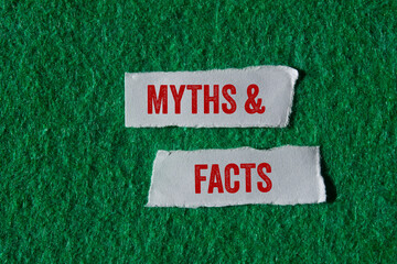 Myths and facts message written on ripped torn paper pieces on green background. Conceptual myths...