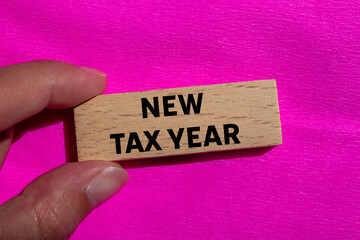 New tax year message written on wooden block on pink background. Conceptual new tax year symbol....