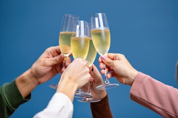 Four people toasting with champagne glasses against a blue background celebrating with a cheerful mood