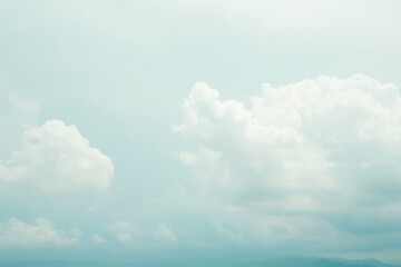 Expansive sky filled with soft, fluffy clouds over a distant horizon with faint mountain silhouettes under serene daylight