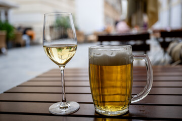 Cold beer and white wine glass on wooden table outdoors in summer garden