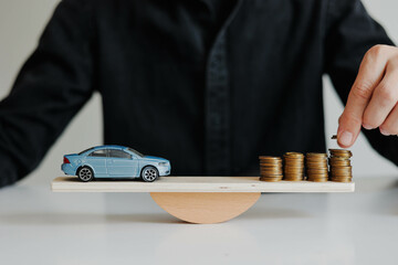 Toy car and coins on wooden balancing scale. The concept of saving money for a future car purchase.