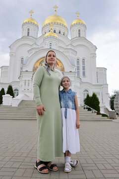 Russian woman in a scarf with a little daughter against the background of an Orthodox church