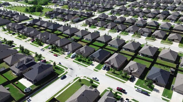 Row of new construction homes with shingle roofing along quite large residential street with young trees immature landscaping at master planned community near Saddle Club Way in Princeton, Texas. US 
