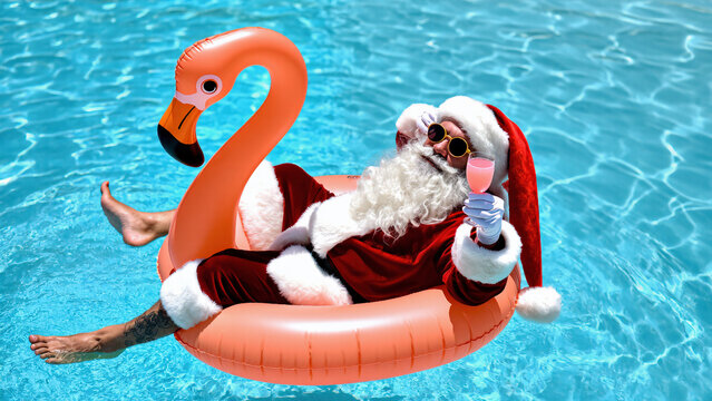 A cheerful elderly man with a white beard wearing a Santa hat and sunglasses is relaxing in a pool on a orange flamingo float while holding a cocktail.