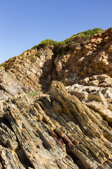 Diagonal Rock Layers and Greenery on Coastal Cliffs near Faro, Portugal