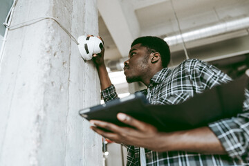 Technician inspecting a smoke alarm in an indoor commercial space during the day