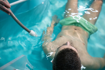 Therapeutic Water Bath.Man relaxing in hydrotherapy bath while therapist adjusts water settings.