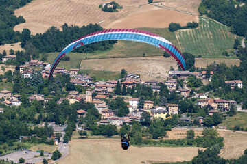Sestola, Italy – 05 31 2025: Paraglider flies in the air. Aerial view of paragliding. Paraglider flies above the mountains in a bright sunny day. Concept of extreme sport.
