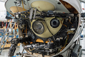 Front view of a complex deep-sea submersible with exposed mechanical arms, wires, and round observation windows, showcasing advanced underwater technology in a scientific laboratory.
