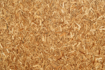 Closeup view of oriented strand board (OSB) surface with chaotic wood chips texture, suitable for construction, design, or background use.