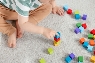 Cute little child playing with colorful cubes at home, above view