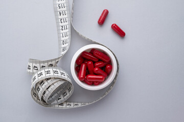 Measuring tape and tablets, vitamins on a light background with space for text. Concept of losing weight, dieting, burning fat, healthy eating.  