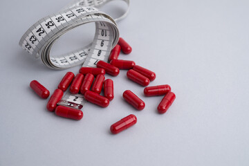Measuring tape and tablets, vitamins on a light background with space for text. Concept of losing weight, dieting, burning fat, healthy eating.  