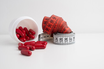 Measuring tape and tablets, vitamins on a light background with space for text. Concept of losing weight, dieting, burning fat, healthy eating.  