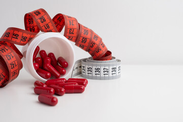 Measuring tape and tablets, vitamins on a light background with space for text. Concept of losing...