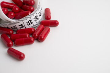 Measuring tape and tablets, vitamins on a light background with space for text. Concept of losing weight, dieting, burning fat, healthy eating.  