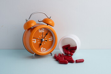 Time to take pills. Alarm clock shows time to take medicine. Taking vitamins or medicine. Concept of health care, medicine, pharmacy, disease prevention