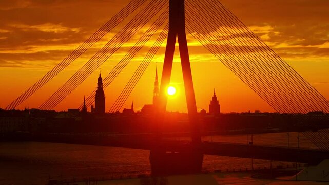 Warm orange sunrise glows behind church towers as drone slowly drifts left