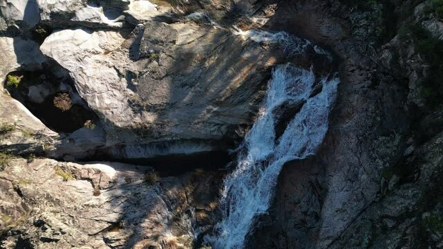 Aerial flyover of a waterfall with dramatic flowing water and natural landscape