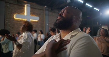 Man in heartfelt worship with hand over heart, glowing cross in background, deep spiritual...