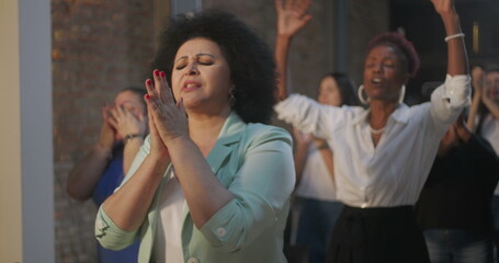 Group of diverse individuals clapping together during an inspiring indoor event, joyful expressions...