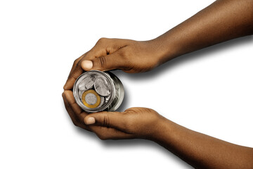 Top flat view of Black Hand holding transparent clear glass bottle jar containing Ghanaian cedis pesewas coins over transparent background. Investment savings and interest concept