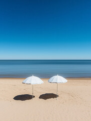 Two white parasols standing on a sandy beach under blue sky