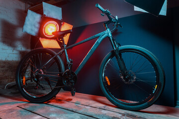 new dark gray bike for teenagers with gear shifting and disc brakes indoors illuminated with red...