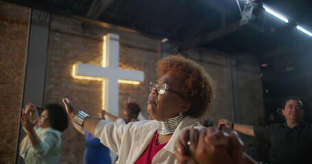 Congregation holding hands during worship, standing in unity and faith, illuminated cross in the background symbolizing community and spiritual connection