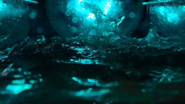 The texture of the water is a rumbling chaos with bubbles created by the air escaping outside in the blue light.